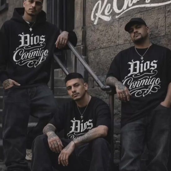 Three men wearing oversized black Dios Conmigo t-shirts standing and sitting on urban steps with Ke Chingon logo on wall streetwear video by Ke Chingon