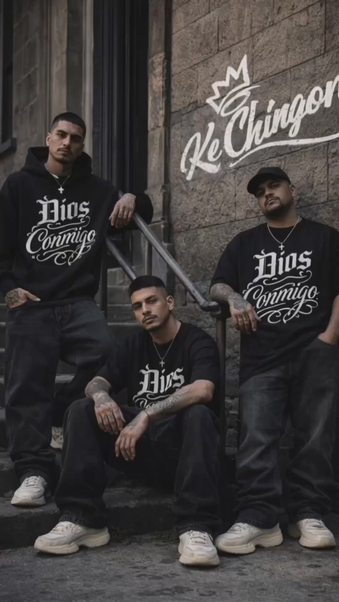 Three men wearing oversized black Dios Conmigo t-shirts standing and sitting on urban steps with Ke Chingon logo on wall streetwear video by Ke Chingon